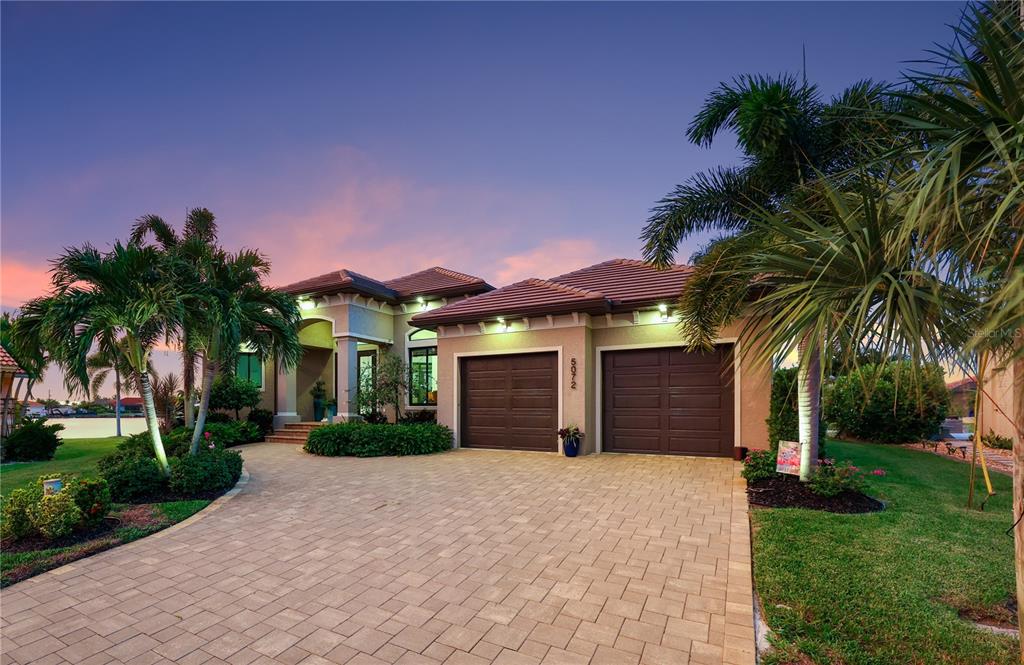 A single-story house with a paved driveway, two-car garage, and palm trees at dusk — 5072 SAN MASSIMO DRIVE, PUNTA GORDA, FL
