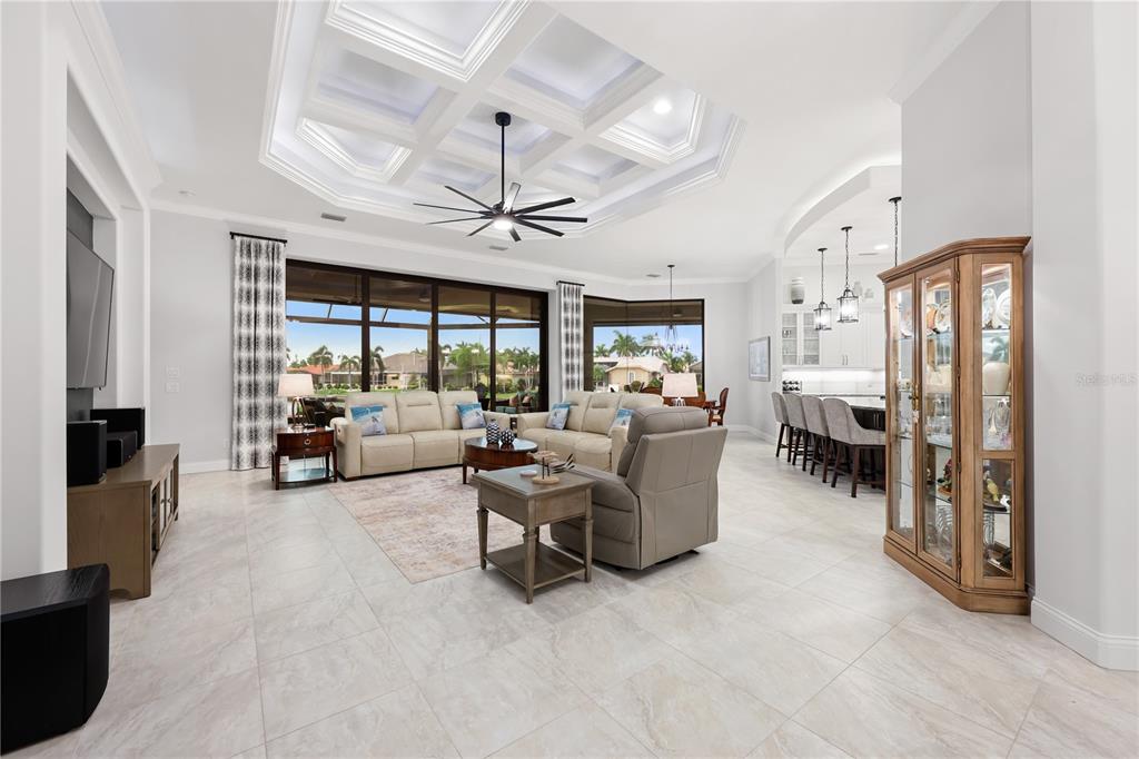 A spacious living room features a coffered ceiling, large windows, and an open-concept kitchen — 5072 SAN MASSIMO DRIVE, PUNTA GORDA, FL
