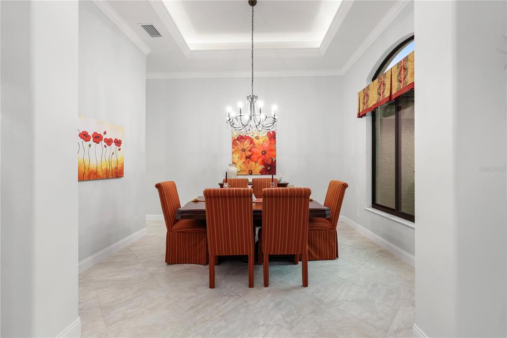 A formal dining room features a chandelier, a wooden table, and six striped orange chairs — 5072 SAN MASSIMO DRIVE, PUNTA GORDA, FL