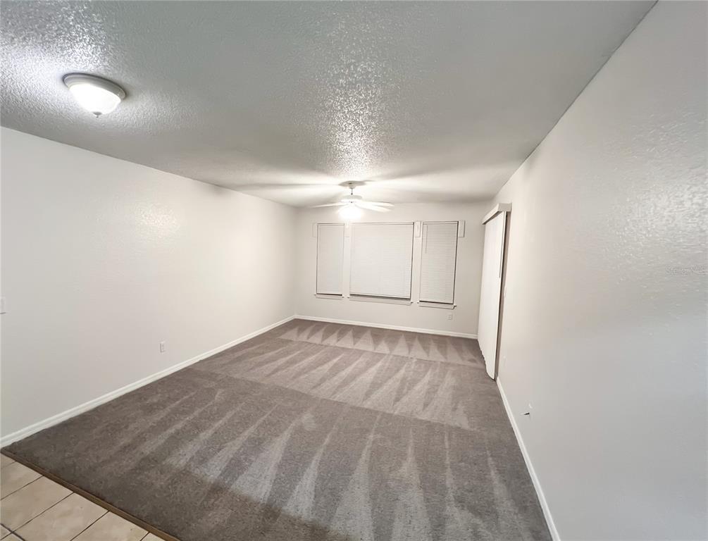 A carpeted bedroom with white walls, a ceiling fan, and a window with blinds — 1023 S HIAWASSEE ROAD UNIT 4013, ORLANDO, FL