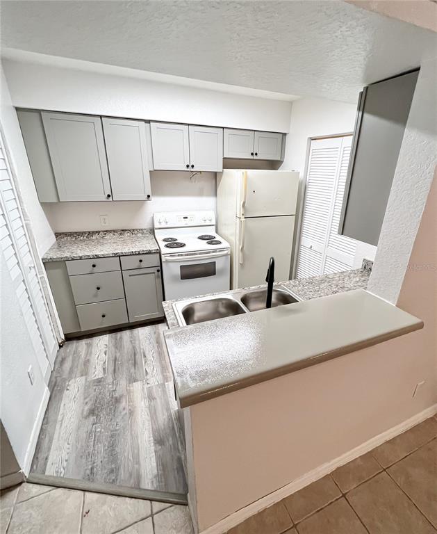 A kitchen features gray cabinets, speckled countertops, a white stove, and wood-look flooring — 1023 S HIAWASSEE ROAD UNIT 4013, ORLANDO, FL