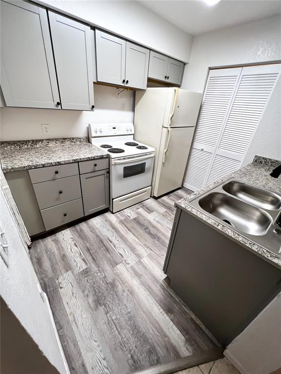 A kitchen features gray cabinets, granite-look countertops, a white stove, and wood-look flooring — 1023 S HIAWASSEE ROAD UNIT 4013, ORLANDO, FL