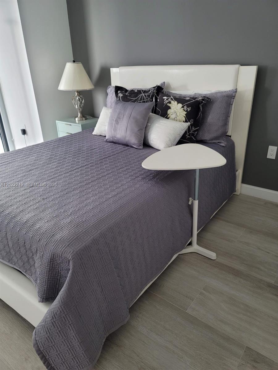 A bedroom features a white headboard, a purple patterned quilt, and a small white side table — 55 SW 9th St # 2709, Miami FL 33130, MIAMI, FL