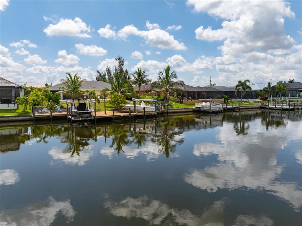 A canal view showing several houses with private boat docks and palm trees — 229 NW 33RD AVENUE, CAPE CORAL, FL