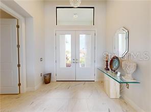 A bright entryway features double glass doors, light-colored tile flooring, and a glass console table — 229 NW 33RD AVENUE, CAPE CORAL, FL