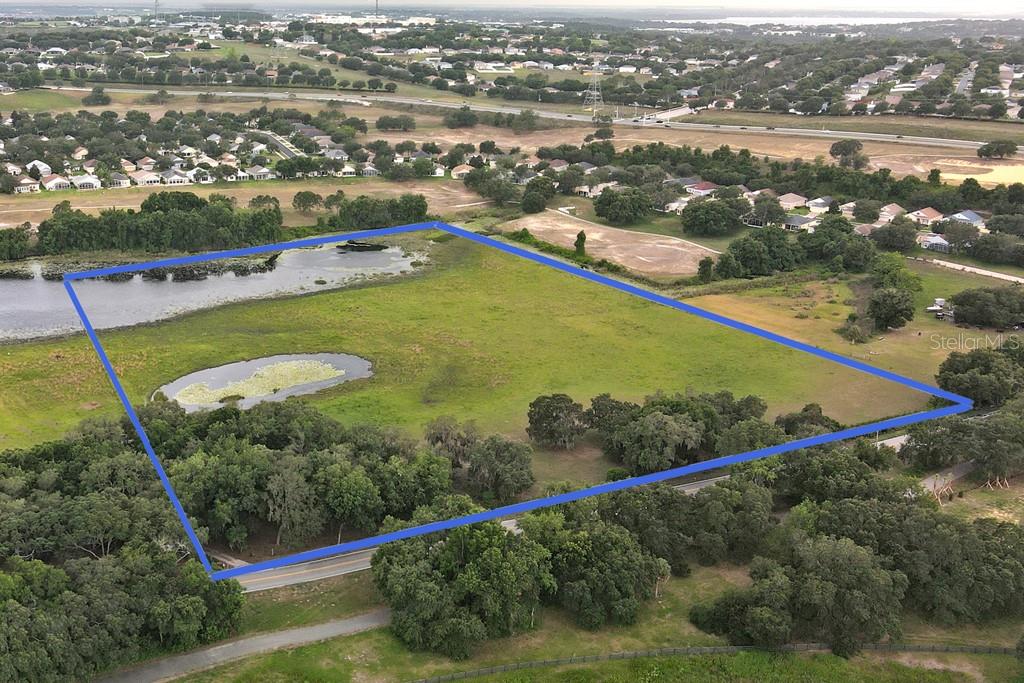 An aerial view shows a large, grassy vacant lot outlined in blue with two ponds — 14704 OLD HIGHWAY 50, CLERMONT, FL