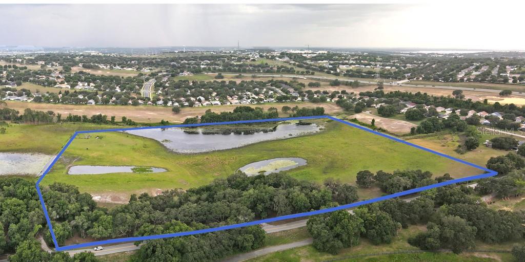 An aerial view shows a large, grassy plot of land with ponds outlined in blue — 14704 OLD HIGHWAY 50, CLERMONT, FL