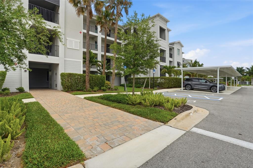 A multi-story apartment building with a paved walkway, landscaping, and a covered parking area — 14131 HERITAGE LANDING BOULEVARD UNIT 846, PUNTA GORDA, FL