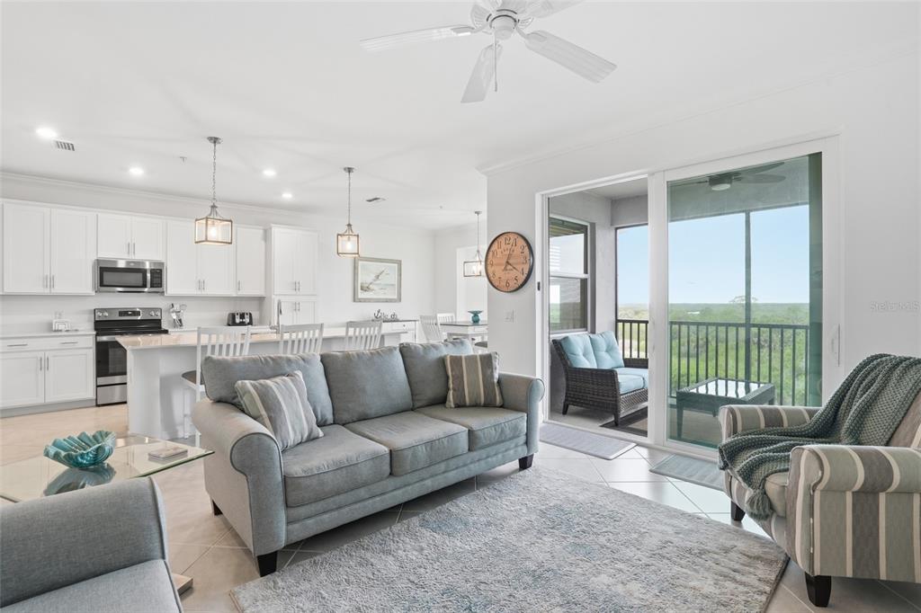 A living room with a gray sofa, area rug, and sliding glass doors to a balcony — 14131 HERITAGE LANDING BOULEVARD UNIT 846, PUNTA GORDA, FL
