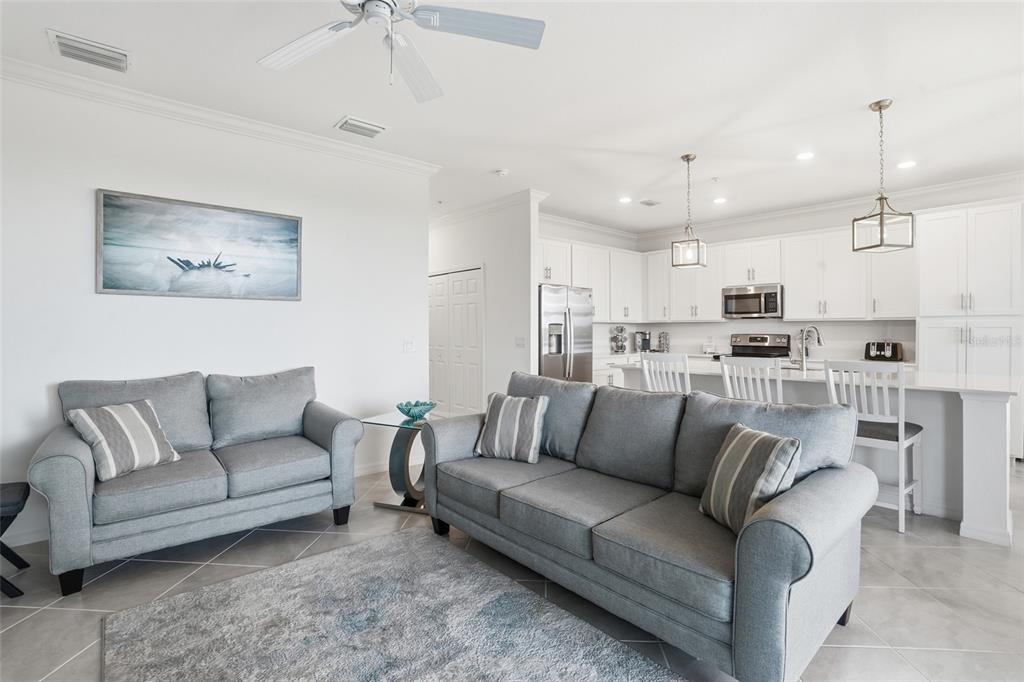 A living room with gray sofas and a rug opens into a white kitchen — 14131 HERITAGE LANDING BOULEVARD UNIT 846, PUNTA GORDA, FL