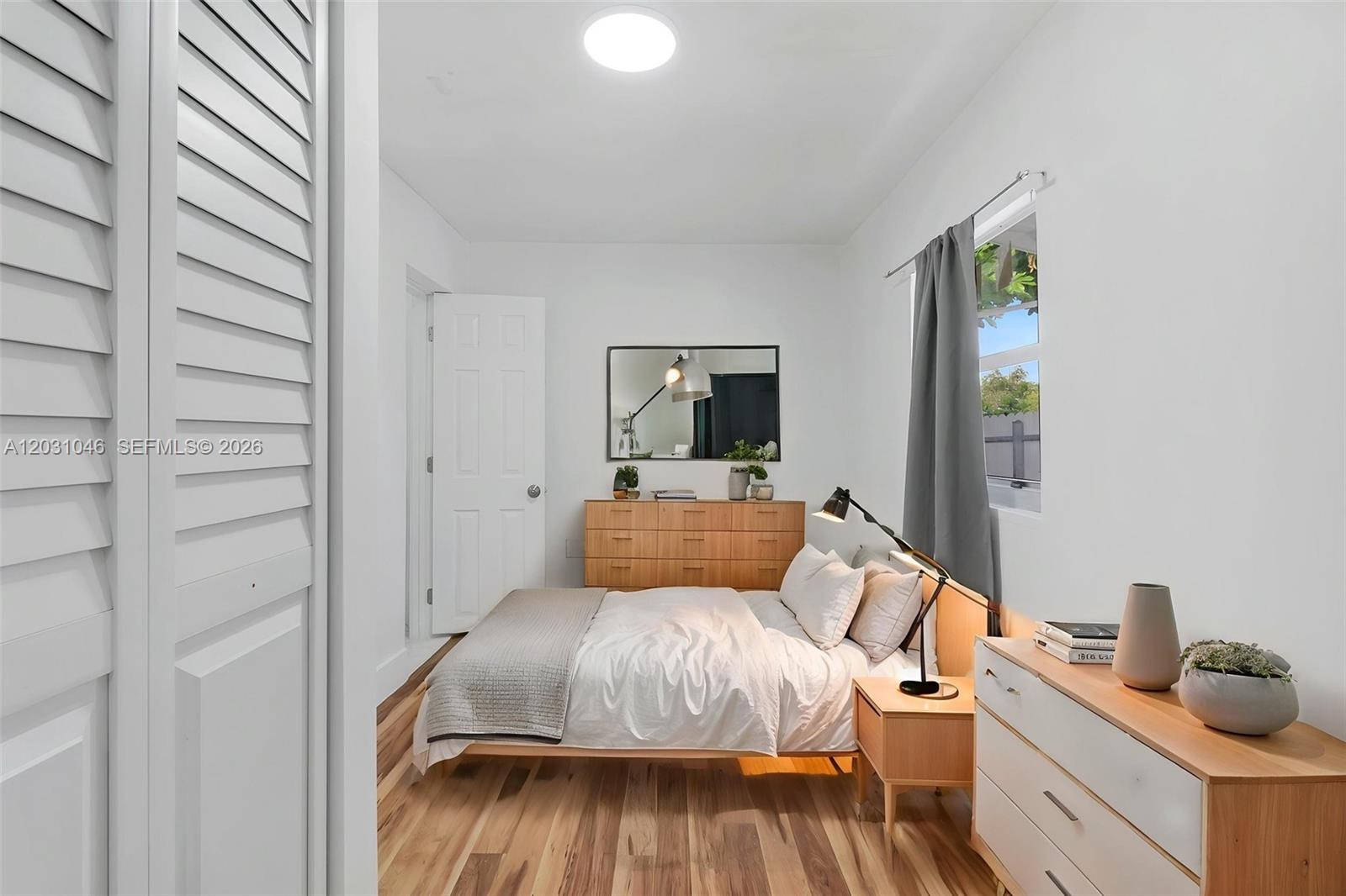 A bedroom features a bed, wooden dresser, nightstand, and white walls with hardwood flooring — 6101 SW 24th St # 2, Miramar FL 33023, MIRAMAR, FL