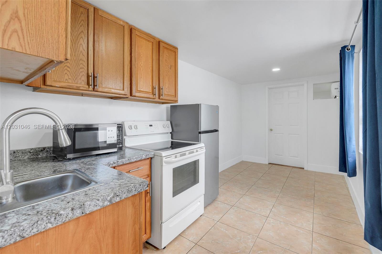 A kitchen features wood cabinets, granite countertops, a white stove, and a stainless steel refrigerator — 6101 SW 24th St # 2, Miramar FL 33023, MIRAMAR, FL