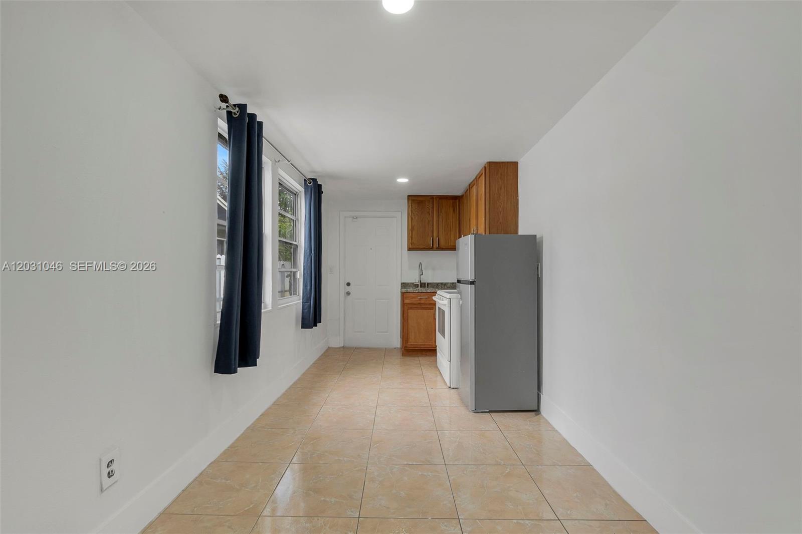 A narrow kitchen features tile flooring, wood cabinets, a white stove, and a refrigerator — 6101 SW 24th St # 2, Miramar FL 33023, MIRAMAR, FL