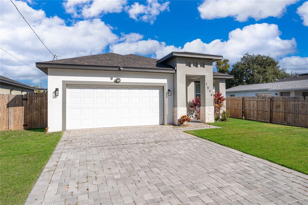 A single-story house with a white garage, stone accents, and a paved driveway — 1519 INDIANA STREET, ORLANDO, FL