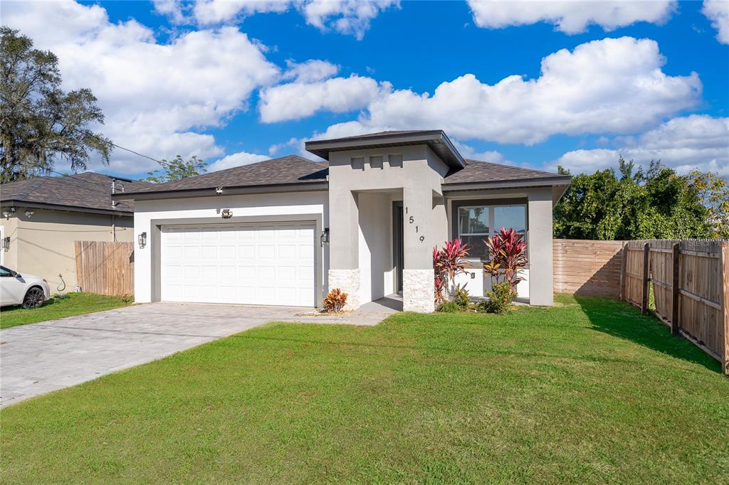 A single-story house with a white garage, gray stucco exterior, and a small front lawn — 1519 INDIANA STREET, ORLANDO, FL