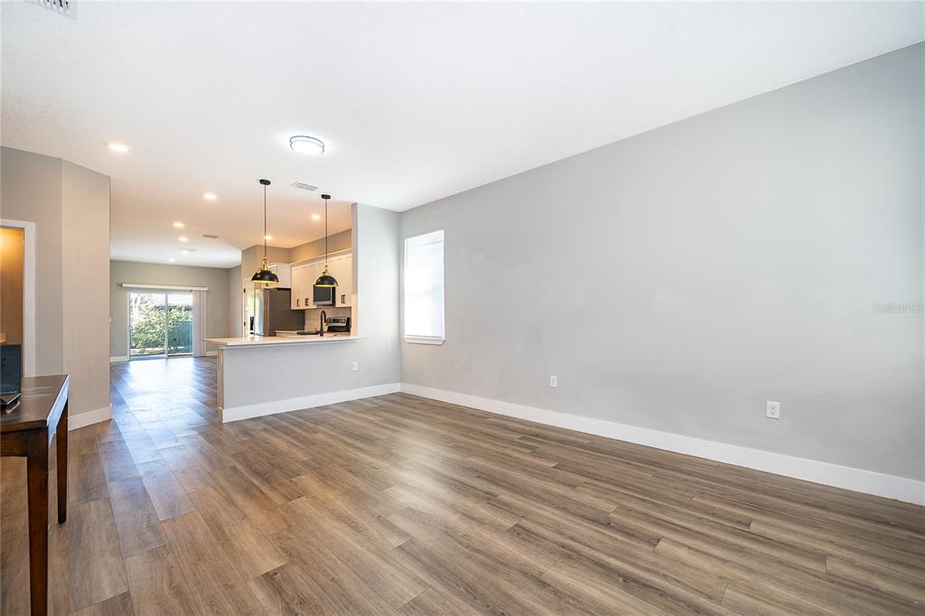 An open-concept living area features light gray walls, wood-look flooring, and a kitchen breakfast bar — 1519 INDIANA STREET, ORLANDO, FL