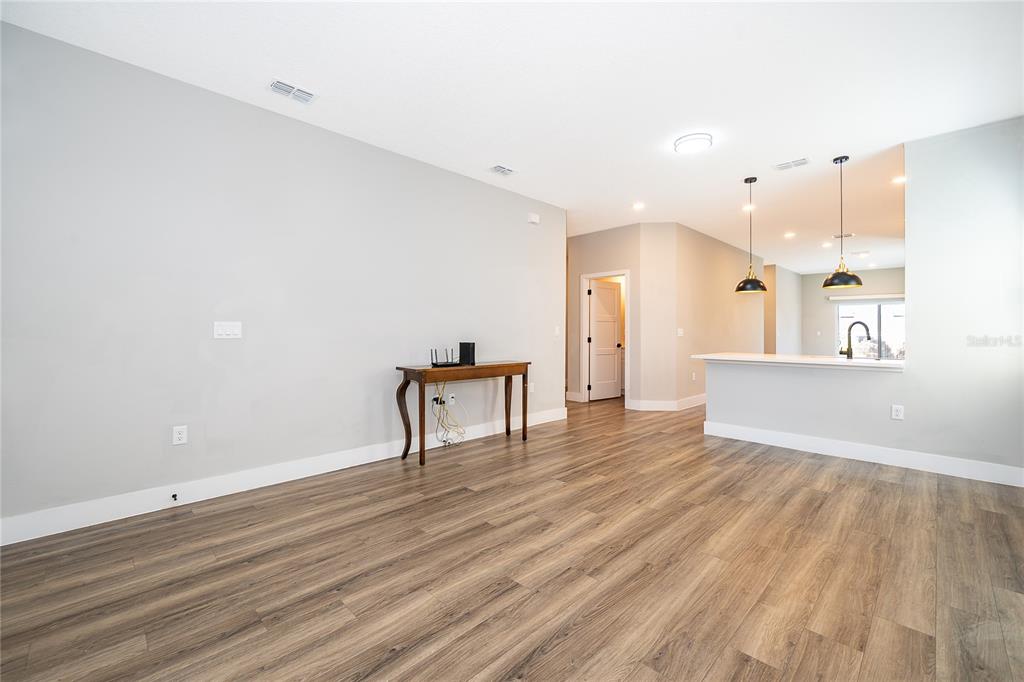 A living room with light gray walls, wood-look flooring, and an open kitchen breakfast bar — 1519 INDIANA STREET, ORLANDO, FL