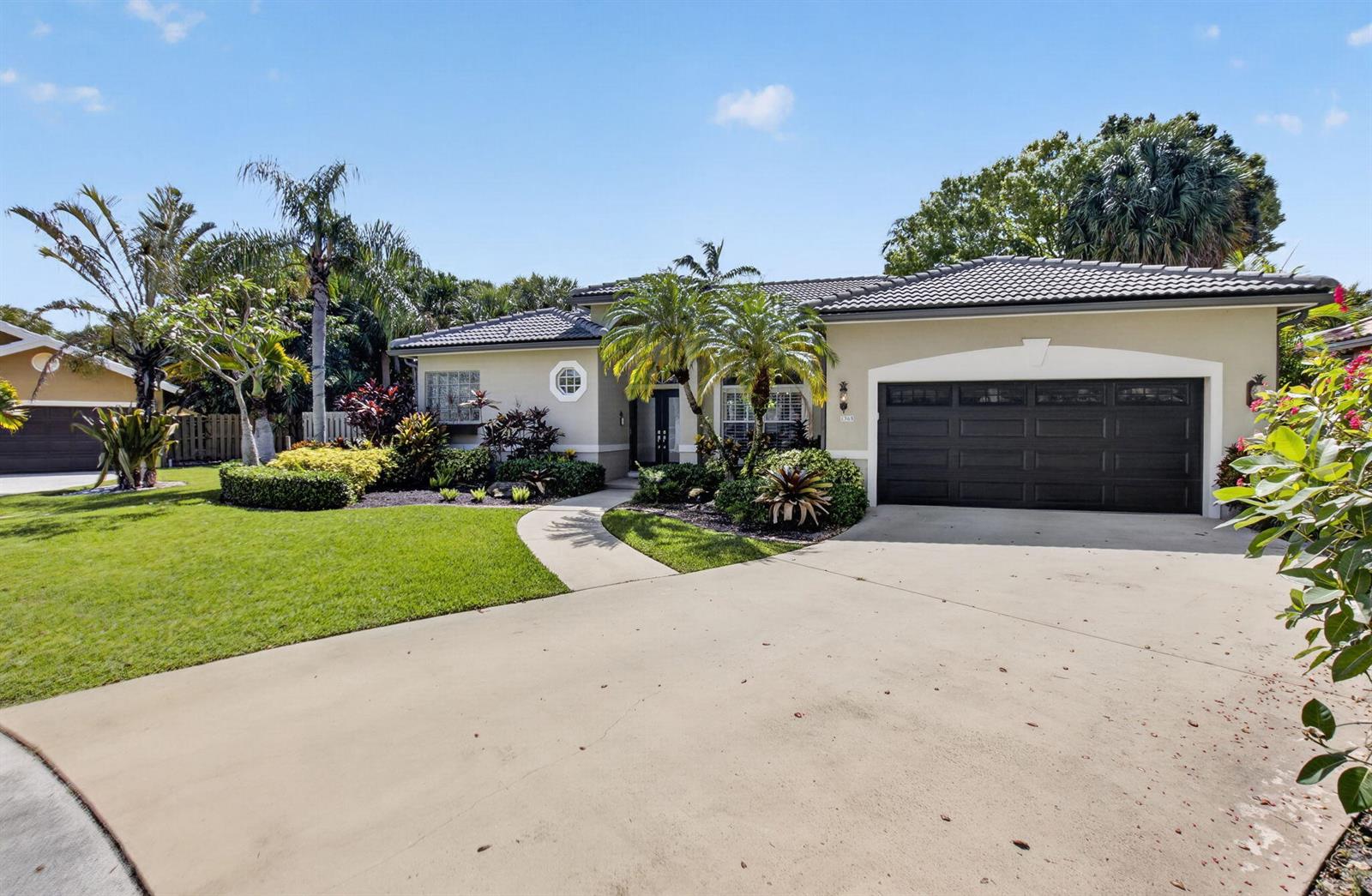 A single-story house with a beige exterior, dark garage door, and tropical landscaping — 1365 E Barwick Ranch Circle, Delray Beach FL 33445, DELRAY BEACH, FL