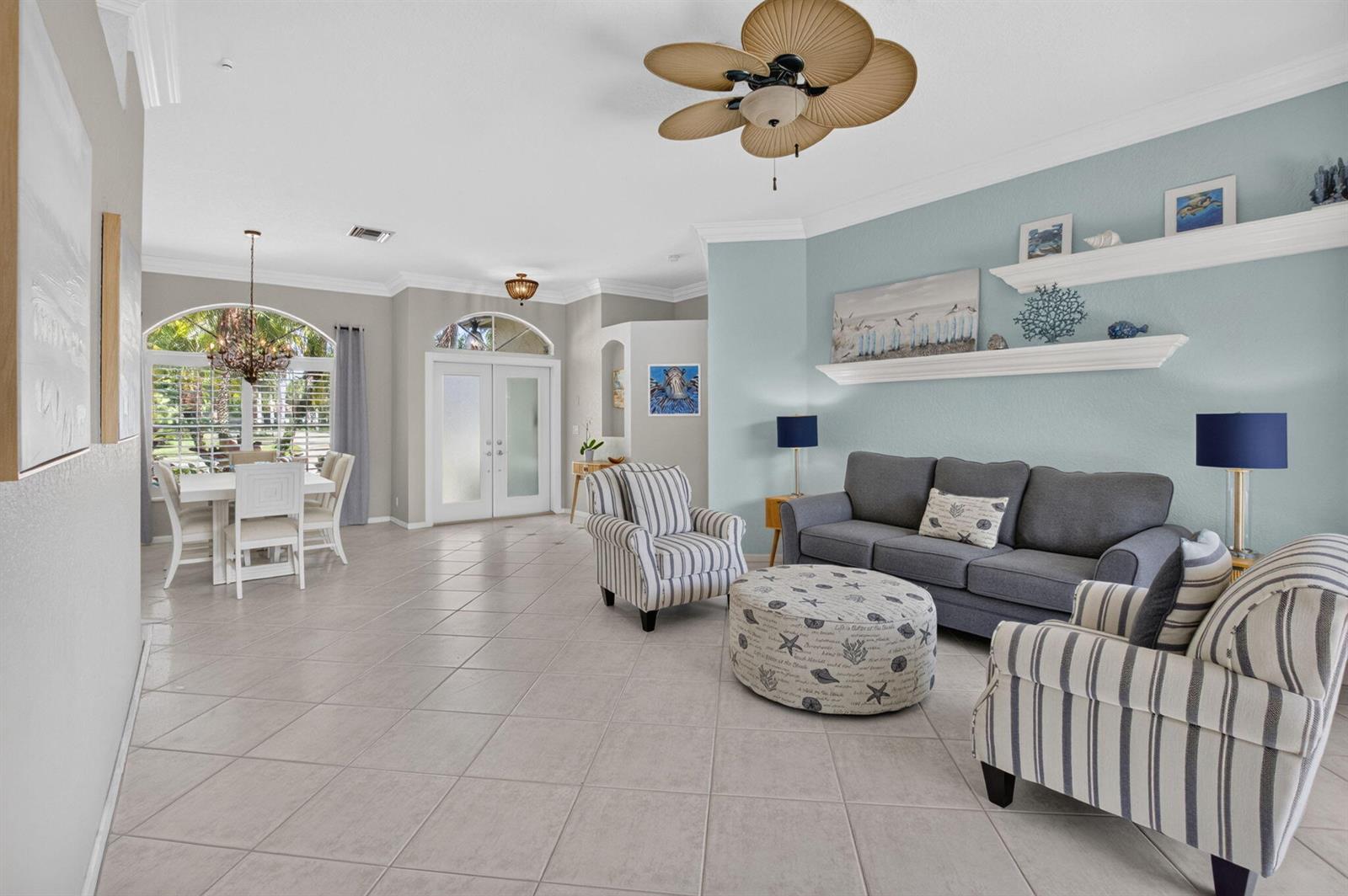 A living room with light blue walls, a grey sofa, striped armchairs, and tile flooring — 1365 E Barwick Ranch Circle, Delray Beach FL 33445, DELRAY BEACH, FL
