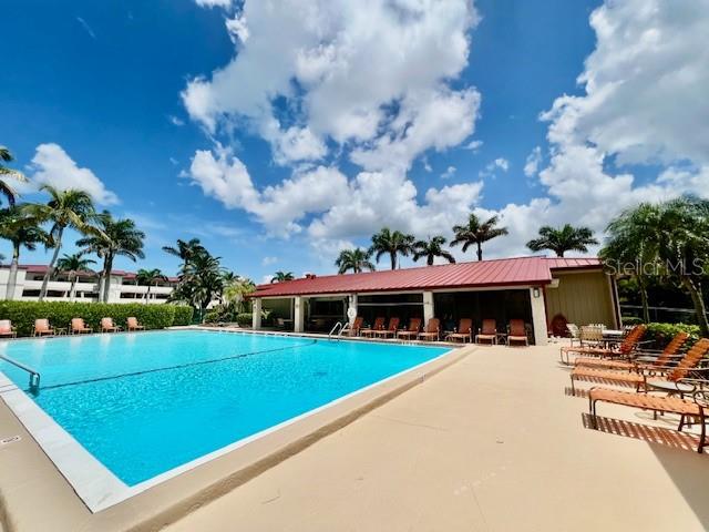 A swimming pool sits in front of a building with a red metal roof — 3280 SOUTHSHORE DRIVE UNIT 85C, PUNTA GORDA, FL