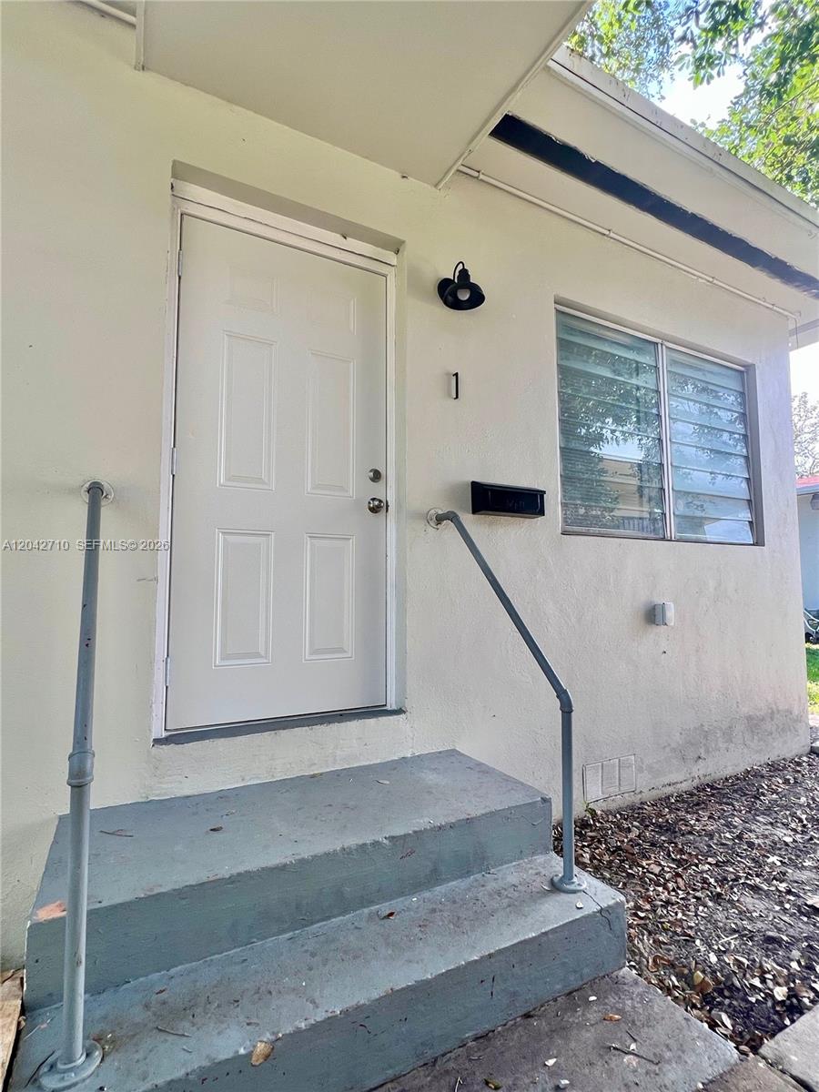 A white exterior wall features a front door, a window, and metal handrails on steps — 962 NW 6th St # 1, Miami FL 33136, MIAMI, FL