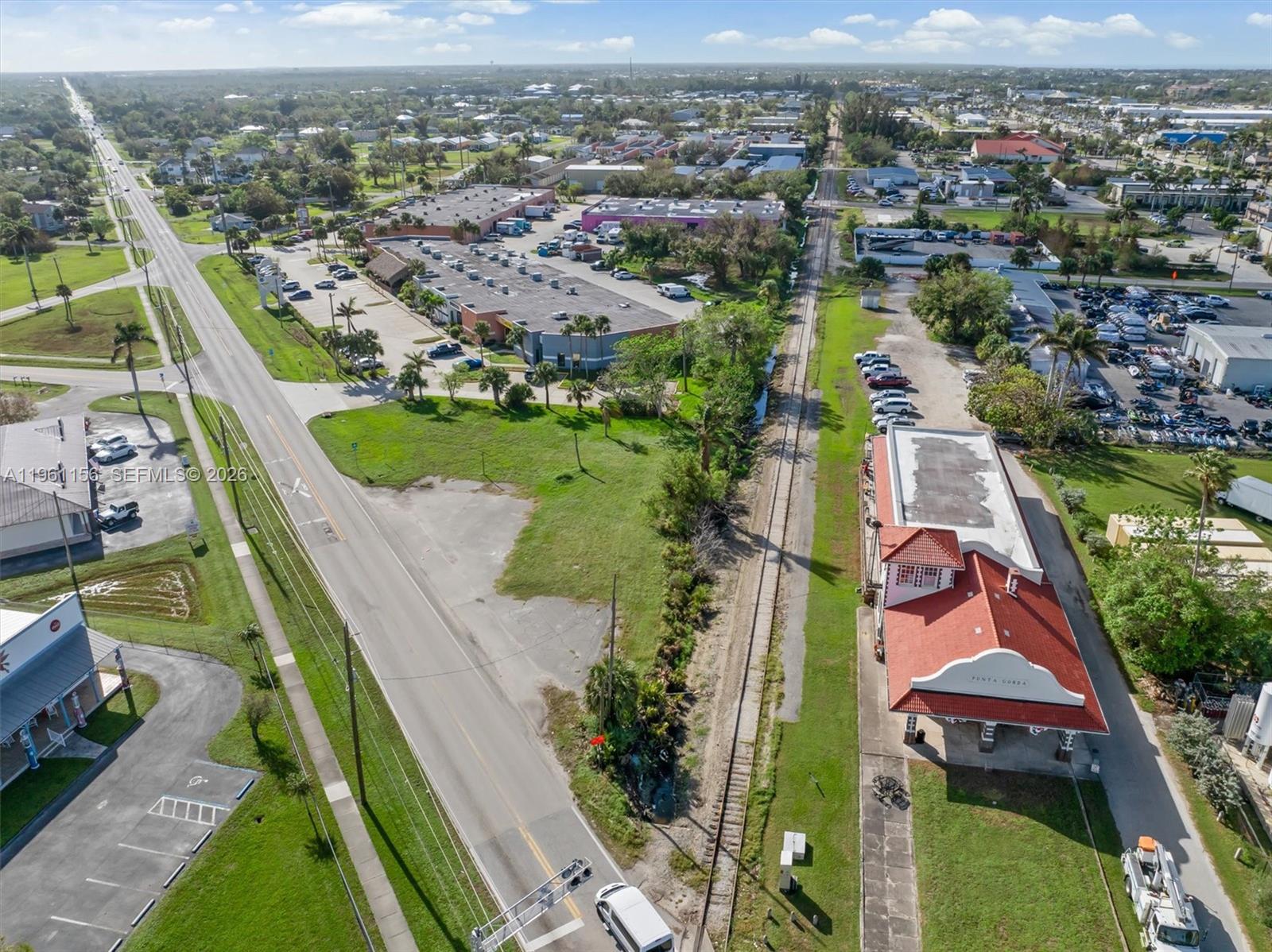 An aerial view shows a road, railroad tracks, and a building with a red roof — 1013 Taylor Rd, Punta Gorda FL 33950, PUNTA GORDA, FL