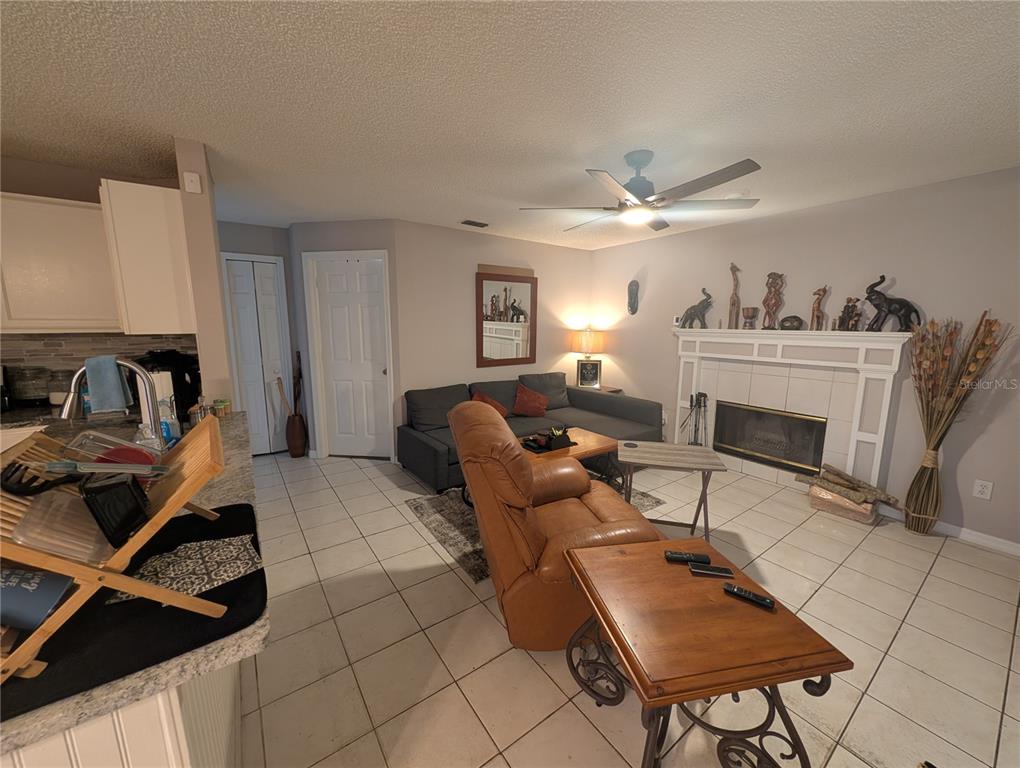 A living room features a fireplace, a leather recliner, a gray sofa, and tiled floors — 770 SWEETBRIER DRIVE, DELTONA, FL