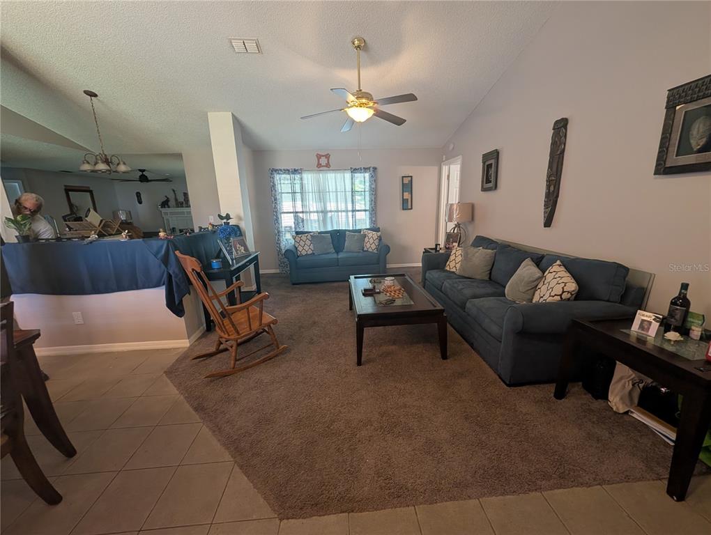 A living room features a gray sectional sofa, a leather recliner, and wood tables — 770 SWEETBRIER DRIVE, DELTONA, FL