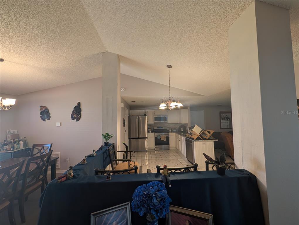 A kitchen features white cabinets, stainless steel appliances, granite countertops, and white tile flooring — 770 SWEETBRIER DRIVE, DELTONA, FL