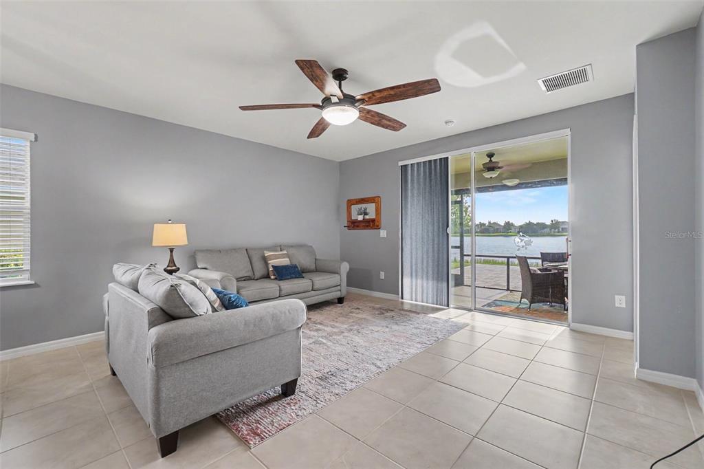 A living room features gray walls, tile flooring, a ceiling fan, and sliding glass doors — 7136 CRYSTAL WAY, PUNTA GORDA, FL