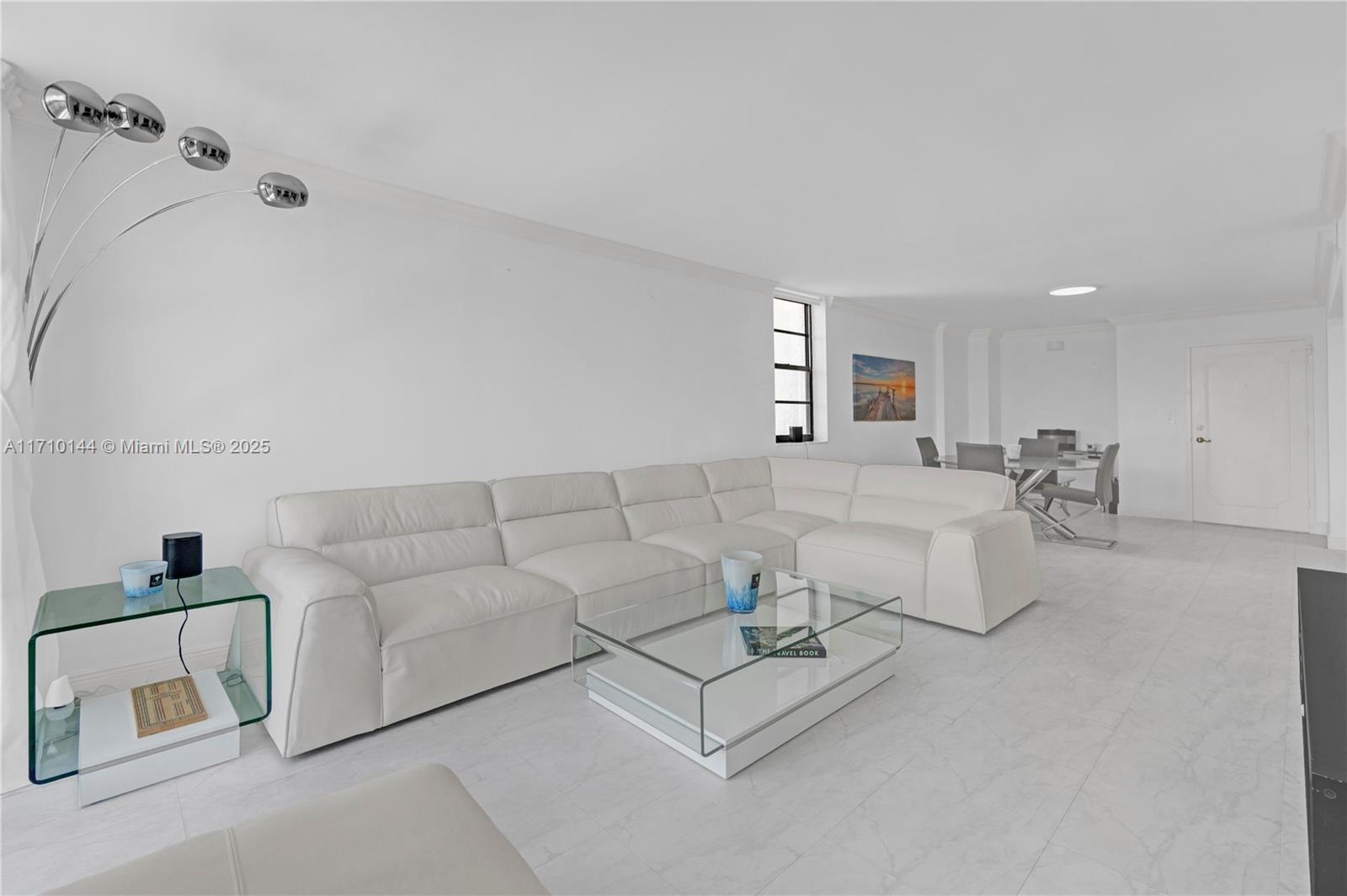A bright living room features a white sectional sofa, a glass coffee table, and tile flooring — 1600 S Ocean Dr # 2F, Hollywood FL 33019, HOLLYWOOD, FL