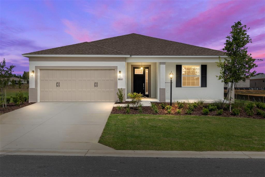 A single-story house with a two-car garage, white stucco exterior, and a dark front door — 10321 SW 107TH COURT, OCALA, FL