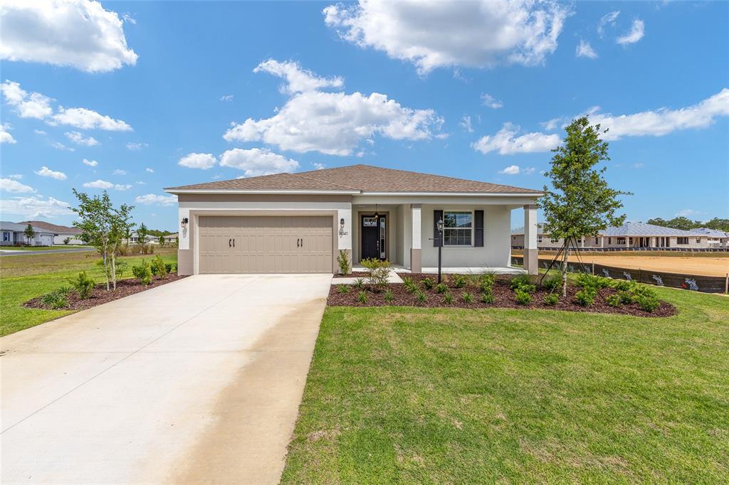 A single-story suburban house with a tan garage, light-colored stucco exterior, and a concrete driveway — 10321 SW 107TH COURT, OCALA, FL