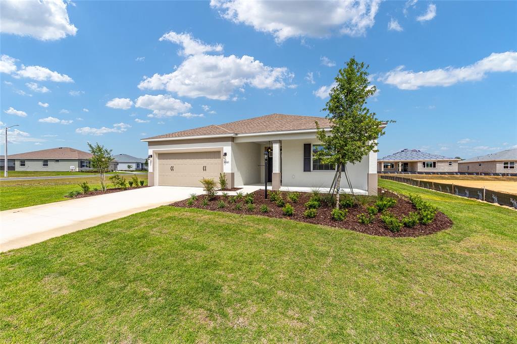 A single-story suburban house with a tan garage and a landscaped front yard — 10321 SW 107TH COURT, OCALA, FL