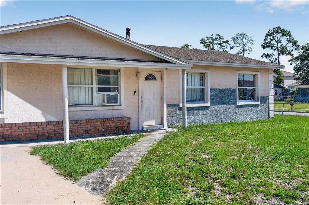 A single-story house with a beige stucco exterior, brick accents, and a front walkway — 1602 S PATRICK CIRCLE, DAYTONA BEACH, FL