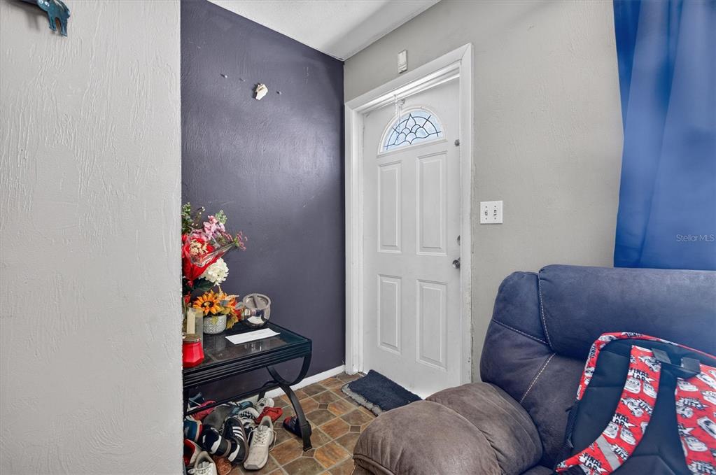 An entryway features a dark accent wall, a glass-topped side table, and a white door — 1602 S PATRICK CIRCLE, DAYTONA BEACH, FL