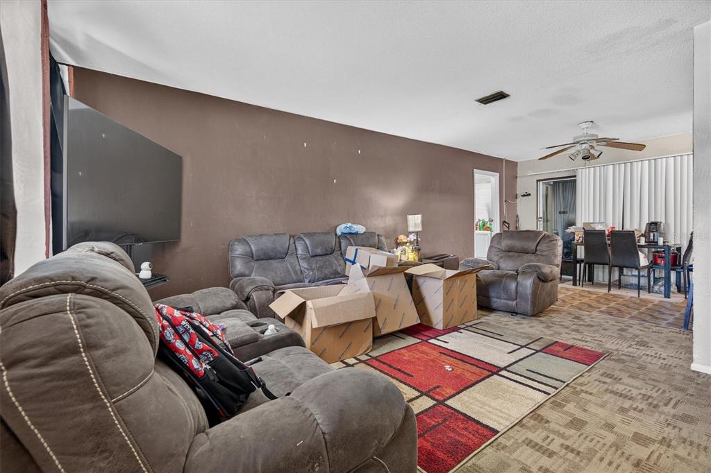 A living room features brown walls, gray reclining furniture, cardboard boxes, and a patterned rug — 1602 S PATRICK CIRCLE, DAYTONA BEACH, FL