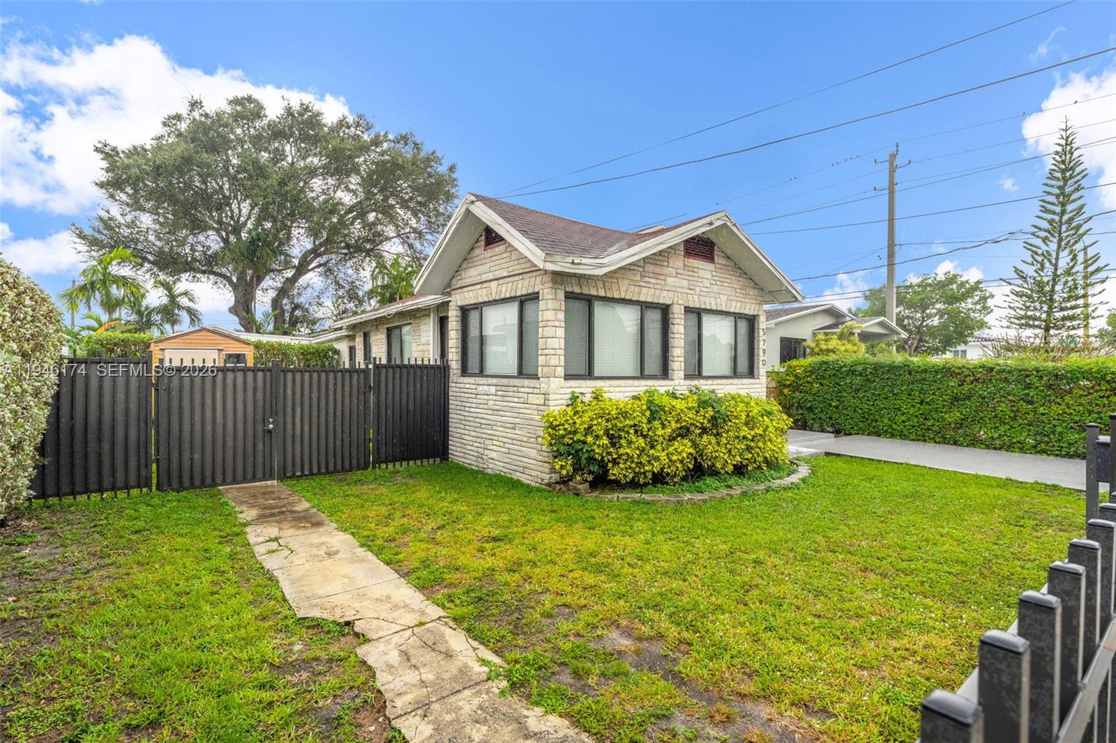 A small, stone-clad house with a front lawn and a black metal fence — 5790 SW 5th St, Miami FL 33144, MIAMI, FL