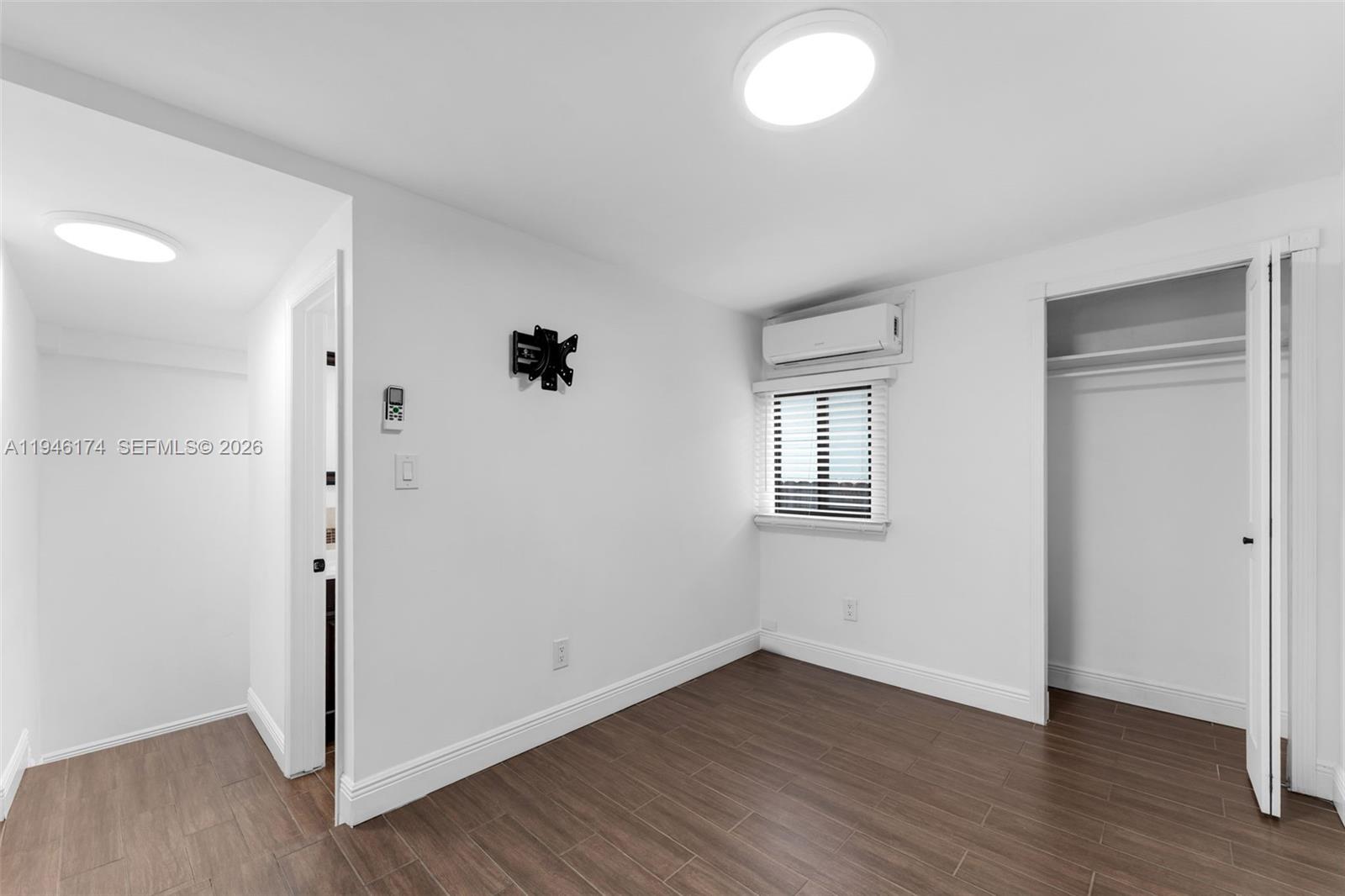 An empty room features white walls, dark wood-look flooring, a window, and a closet — 5790 SW 5th St, Miami FL 33144, MIAMI, FL