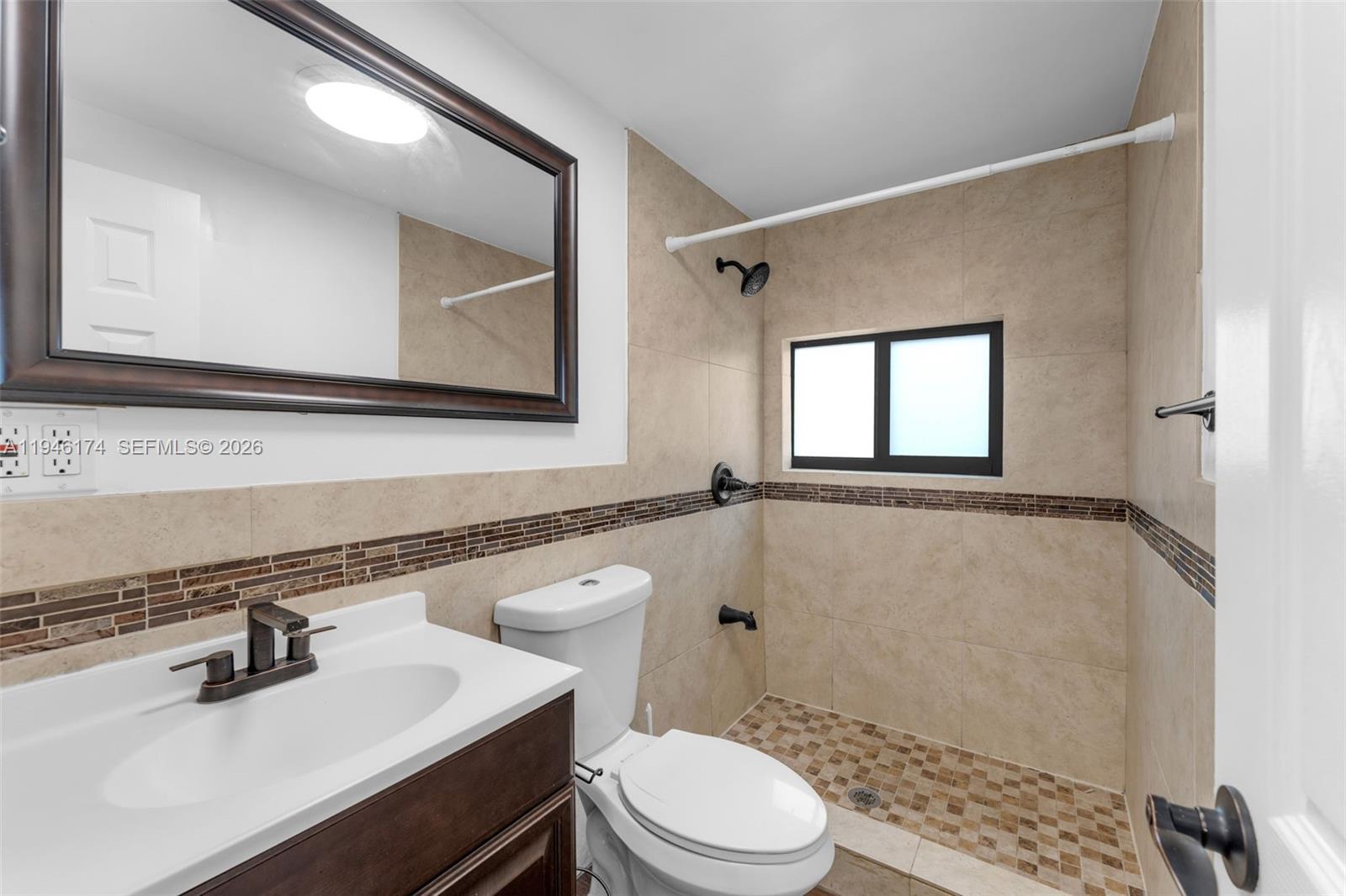 A bathroom features a vanity, toilet, and a tiled walk-in shower with a window — 5790 SW 5th St, Miami FL 33144, MIAMI, FL