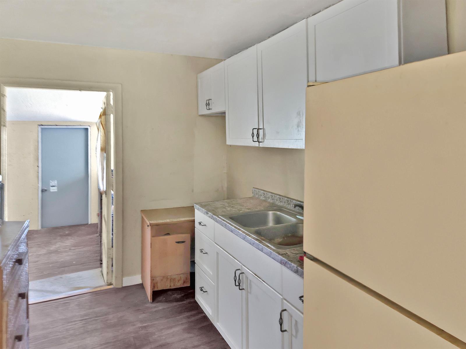 A kitchen features white cabinets, a double sink, and a beige refrigerator on dark flooring — 314 Dickson Drive, Fort Pierce FL 34982, FORT PIERCE, FL