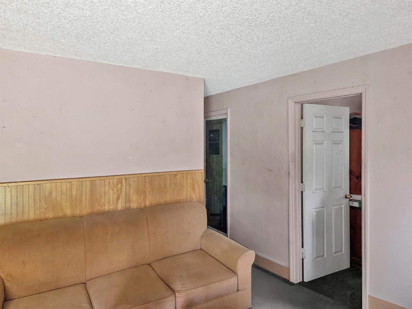A room features a tan sofa against a wall with wood wainscoting and two doorways — 314 Dickson Drive, Fort Pierce FL 34982, FORT PIERCE, FL