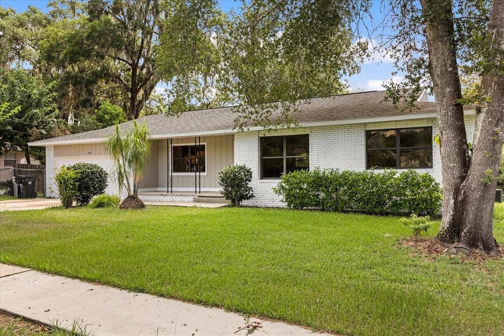A single-story white brick house with a gray shingled roof and a front lawn — 575 LAKE MCCOY DRIVE, APOPKA, FL