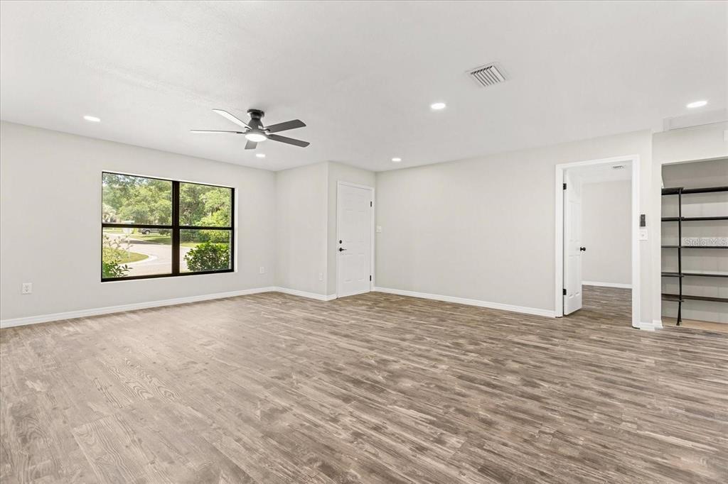 A spacious room with light-colored walls, wood-look flooring, a ceiling fan, and a large window — 575 LAKE MCCOY DRIVE, APOPKA, FL