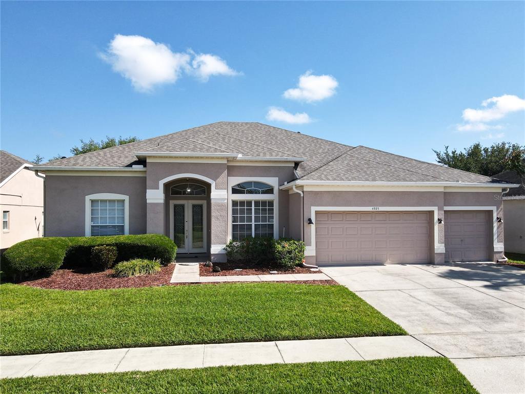 A single-story suburban house features a tan stucco exterior, a gray shingled roof, and a driveway — 4925 BRIGHTMOUR CIRCLE, ORLANDO, FL