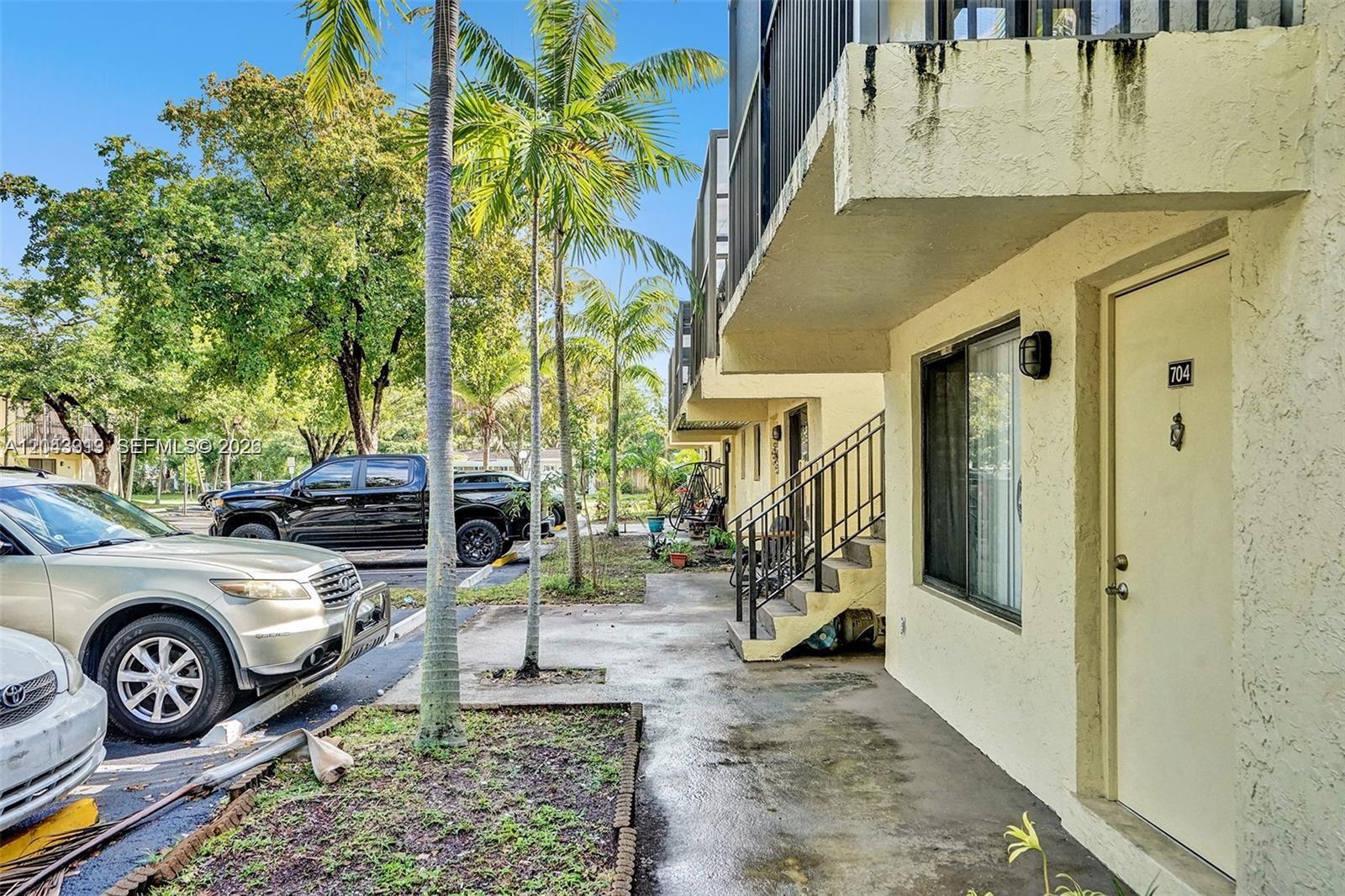 An exterior view of a multi-story apartment building with a parking lot and palm trees — 1065 S Flagler Ave # 704, Pompano Beach FL 33060, POMPANO BEACH, FL