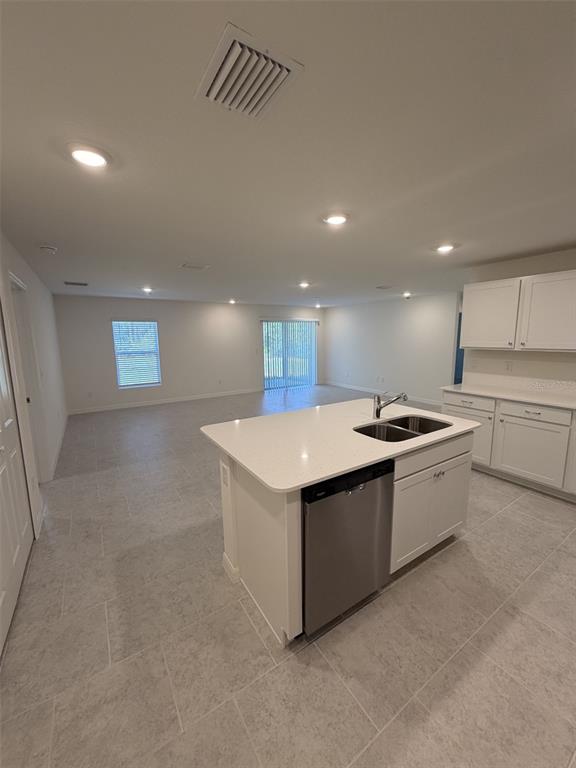 A kitchen island with a stainless steel dishwasher and sink sits in an open-concept room — 10450 BAYLOR AVENUE, HASTINGS, FL