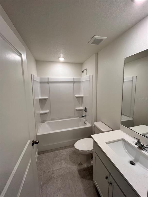 A bathroom features a white vanity, a toilet, and a tub-shower combination with tile flooring — 10450 BAYLOR AVENUE, HASTINGS, FL