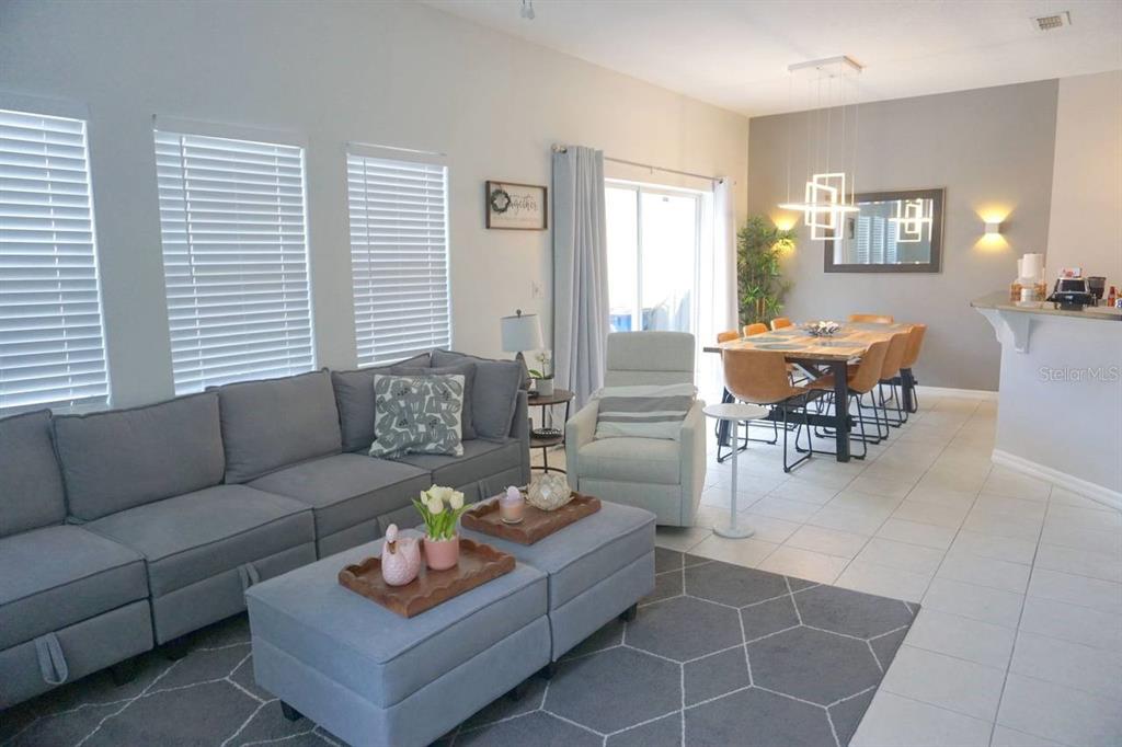 A living room and dining area feature gray tile floors, a sectional sofa, and furniture — 3162 YELLOW LANTANA LANE, KISSIMMEE, FL