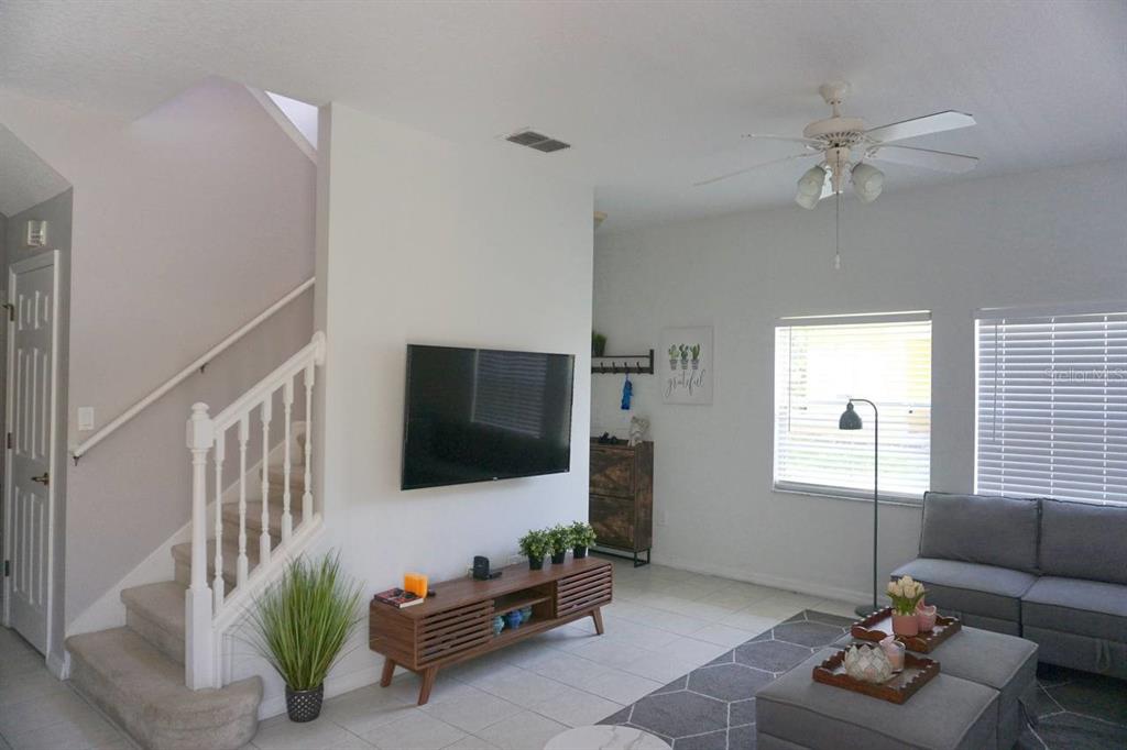A living room features a wall-mounted television, a wooden media console, and a staircase — 3162 YELLOW LANTANA LANE, KISSIMMEE, FL